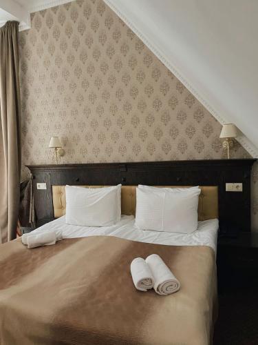 a bedroom with a bed with two towels on it at Hotel Gentleman in Ternopilʼ