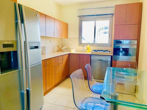 Il comprend une cuisine équipée d'une table en verre et d'un réfrigérateur. dans l'établissement Royal King David Apartment, à Netanya