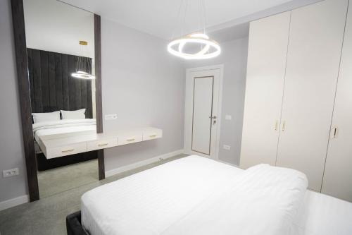 a white bedroom with a bed and a mirror at Deluxe Aparthotel MARWELL RESIDENCE in Suceava