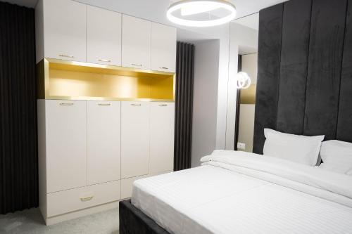 a bedroom with a white bed and white cabinets at Deluxe Aparthotel MARWELL RESIDENCE in Suceava