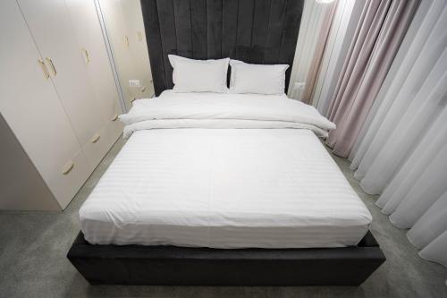 a bed with white sheets and pillows in a room at Deluxe Aparthotel MARWELL RESIDENCE in Suceava
