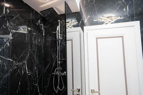 a bathroom with black marble walls and white cabinets at Deluxe Aparthotel MARWELL RESIDENCE in Suceava