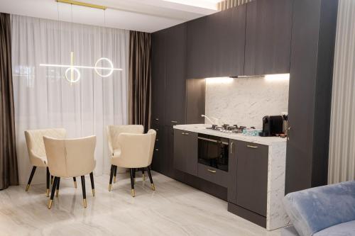 a kitchen with white chairs and a counter and a kitchen with a counter at Deluxe Aparthotel MARWELL RESIDENCE in Suceava