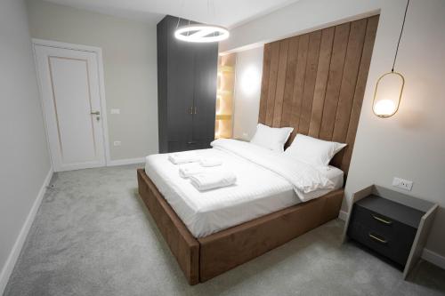 a bedroom with a large bed with a wooden headboard at Deluxe Aparthotel MARWELL RESIDENCE in Suceava