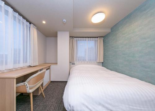 a bedroom with a bed and a desk and a window at Remington Hotel in Akashi