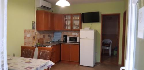 kuchnia z drewnianymi szafkami i białą lodówką w obiekcie Sunshine Apartment w Hajduszoboszlo