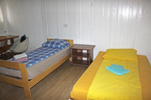 ein Schlafzimmer mit einem Bett mit einer gelben Decke und einem Tisch in der Unterkunft Private Zimmervermietung in Wien