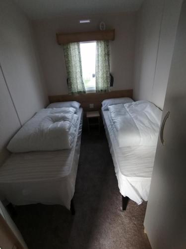 two beds in a small room with a window at 69R Seawick 2 Bedroom Caravan . New for 2022 in Saint Osyth