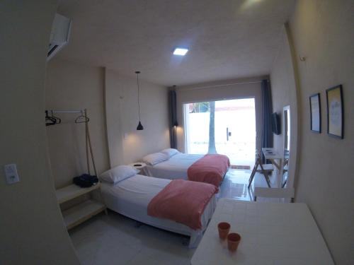 a bedroom with two beds and a window at Flats Taiba Praia Centro in Taíba