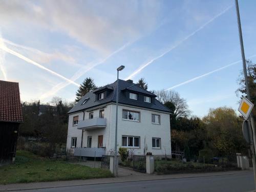 a white house with a black roof on a street at Apartment in Gelb, mit Balkon, Kamin, 50 Schritte zu Radweg, ideal for Long Stay, 4 Singles in Single Rooms in Mainstockheim