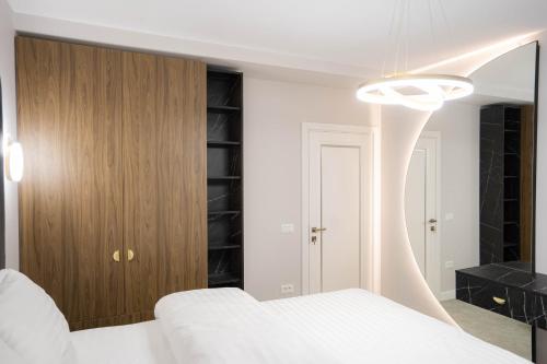 a bedroom with a white bed and a wooden closet at Deluxe Aparthotel MARWELL RESIDENCE in Suceava
