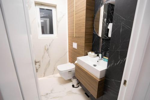 a bathroom with a white toilet and a sink at Deluxe Aparthotel MARWELL RESIDENCE in Suceava