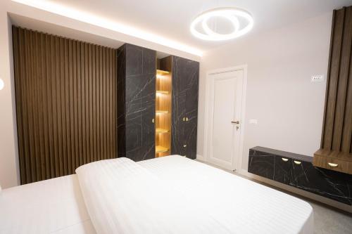 a bedroom with a white bed and a black wall at Deluxe Aparthotel MARWELL RESIDENCE in Suceava