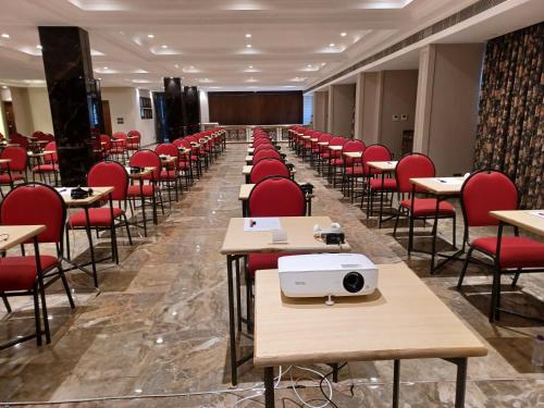 a room with desks and red chairs and a projector at The Cindrella Hotel in Siliguri