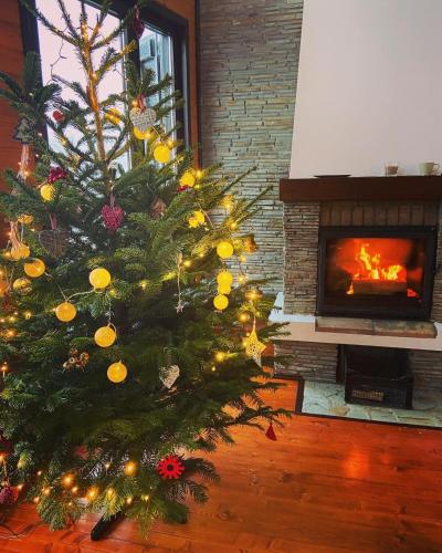 a christmas tree in a living room with a fireplace at Sirnea Chalet in Şirnea