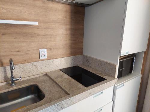 una cucina con lavello e microonde di Hot Beach Suites Olímpia a Olímpia