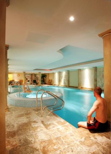 a man sitting in front of a swimming pool at Nailcote Hall in Berkswell