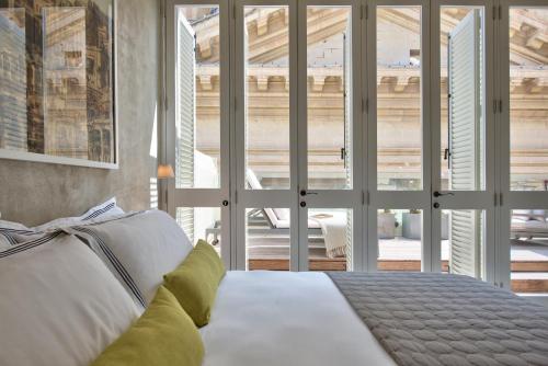 a bedroom with a white bed with a large window at Casa Ellul - Small Luxury Hotels of the World in Valletta