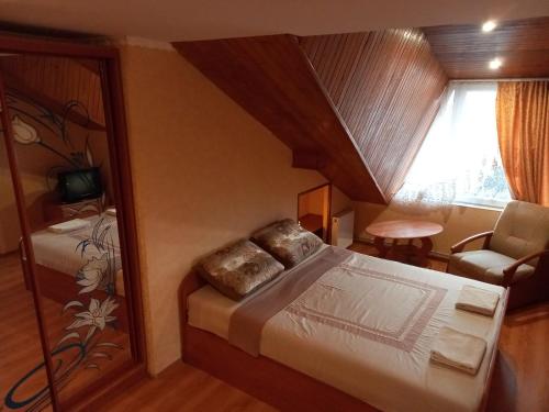 een slaapkamer met een bed, een stoel en een raam bij Приватна садиба in Truskavets