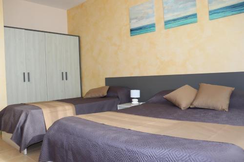 a bedroom with two beds and a cabinet at L'incontro in Trinitapoli
