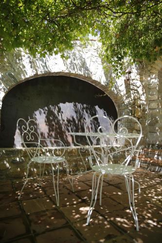 two white chairs and a table under a bridge at L Amourier chambres charme et confort avec Jacuzzi ou baignoire XXL in Saint-Hippolyte-du-Fort