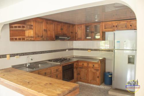 a kitchen with wooden cabinets and a stainless steel refrigerator at Hotel Finca Londres in Villeta