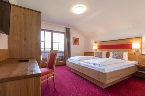 um quarto de hotel com uma cama grande e uma secretária em Landhaus Rosengartl em Schladming