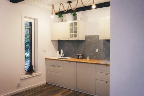 a kitchen with white cabinets and a sink and a window at Domek Izery in Szklarska Poręba