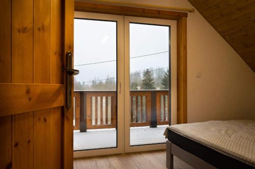 a bedroom with a door open to a balcony at Domek Izery in Szklarska Poręba