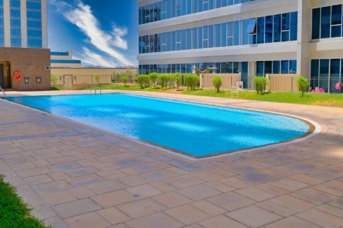 a swimming pool in front of a building at Octavius Holiday Home, Large 2 Bedroom Apartment near Global Village & Outlet Mall in Dubai