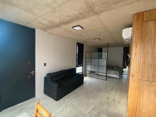 uma sala de estar com um sofá preto num quarto em 126 Suite “Centro” em Suipacha