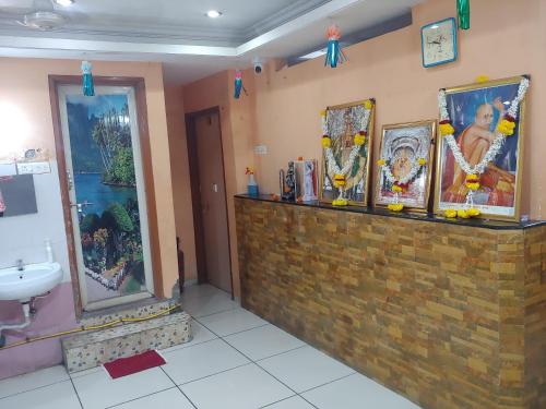 łazienka z blatem z obrazami na ścianie w obiekcie Ambai Deluxe Lodge w mieście Kolhapur