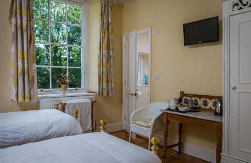 um quarto com uma cama, uma secretária e uma janela em The Old Vicarage B&B em Kenton