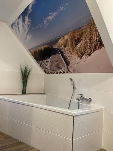 a bathroom with a bathtub with a painting of a beach at Bergstadthütte Harz in Bad Grund