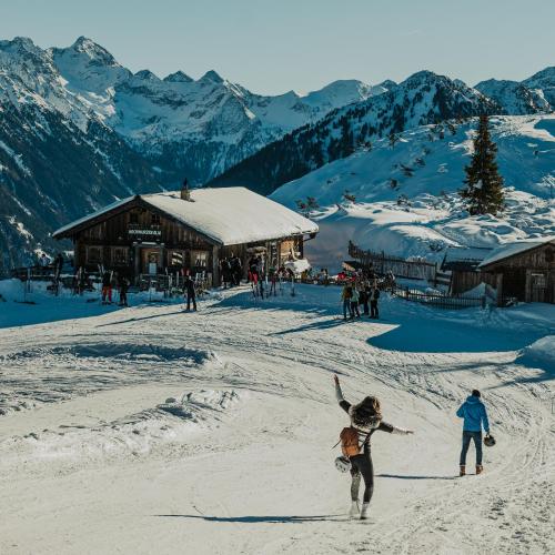 a group of people playing in the snow in front of a ski lodge at Mountain Hotel & Hostel in Ramsau am Dachstein