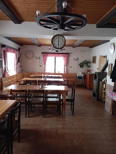 a dining room with tables and a clock on the wall at Penzion Hraničář in Loučná pod Klínovcem