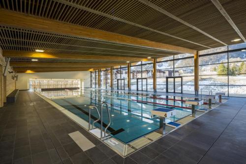 - une grande piscine dans un bâtiment doté de fenêtres dans l'établissement Serrecheholidays, à Serre Chevalier