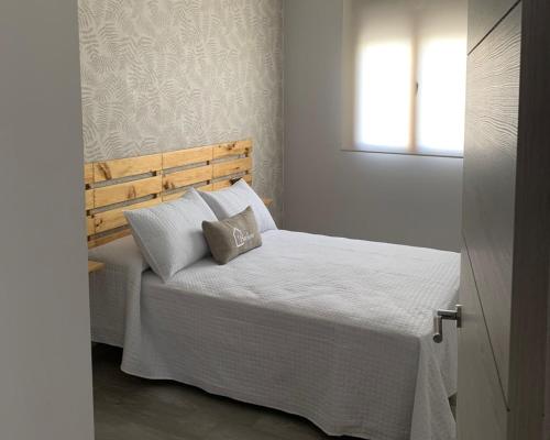 a bedroom with a bed with white sheets and a window at Acogedora casa rural con piscina particularBarlow in Abadía