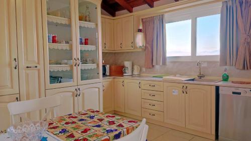 a kitchen with white cabinets and a table and a window at Nikolas House in Corfu