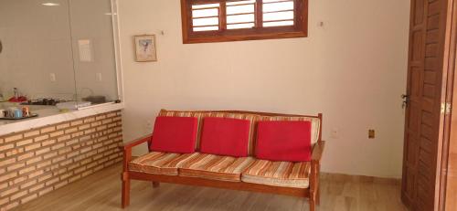 um banco com duas almofadas vermelhas na cozinha em Casa Tropicana em Flecheiras