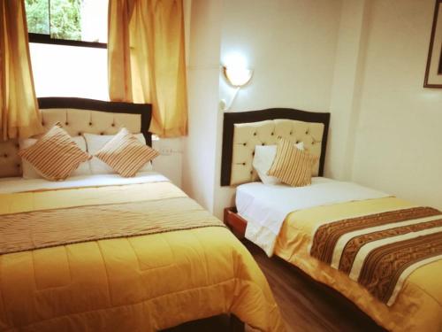 a bedroom with two beds and a window at Hostal Encanto Machupicchu in Machu Picchu