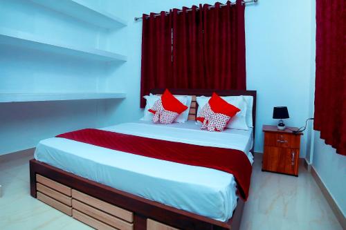 Bethel Service Villa, Mananthavady, Wayanad في واياناد: غرفة نوم بسرير ومخدات حمراء وبيضاء
