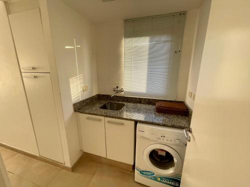 a small kitchen with a washing machine and a sink at Quartier Punta Ballena 2 dorm en suite in Punta del Este