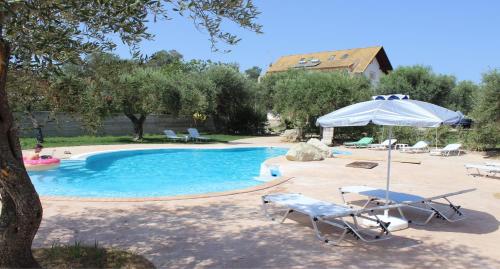 a pool with two chairs and an umbrella and a table at ANEMOMYLOS Lefkimmi LUXUS SUITES-BOUTIQUE HOTEL & POOL in Lefkímmi