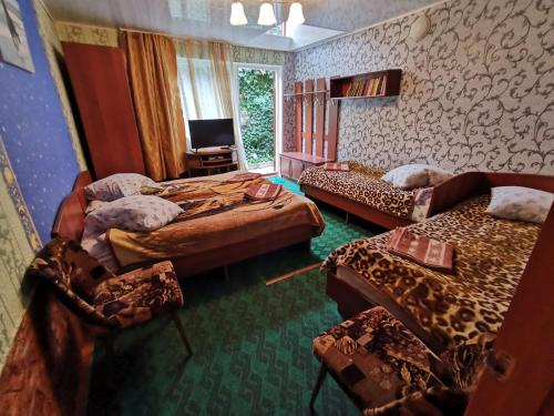 Habitación con 3 camas, sofá y TV. en Petrovskaya Pristan 2 en Cholpon-Ata