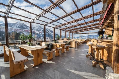 a restaurant with tables and chairs and mountains in the background at Alpendorf Hotel Stern in Sankt Johann im Pongau