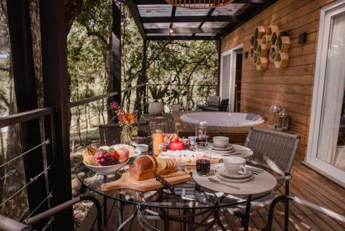 a table with bread and fruit on a porch with a tub at Vila Nambu - Exclusive Pousada in Gramado