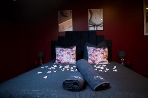 a bed with two pillows and flowers on it at PARENTHESE LOVE - Amour & Tentation Suite Balnéo SPA Proche Orly-Paris in La Ville-du-Bois