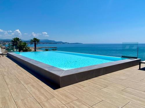 une piscine avec l'océan en arrière-plan dans l'établissement Appartement climatisé les pieds dans l'eau pour 6 personnes avec 1 suite parentale, 1 chambre double et 1 mini chambre Piscine sur le toit clim garage, à Villeneuve-Loubet