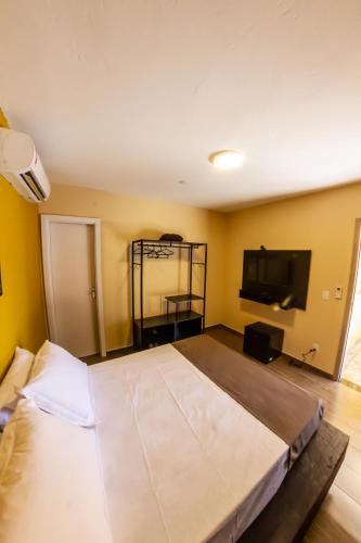a bedroom with a large bed and a tv at Bonabrigo Hostel & Suítes in Balneário Camboriú